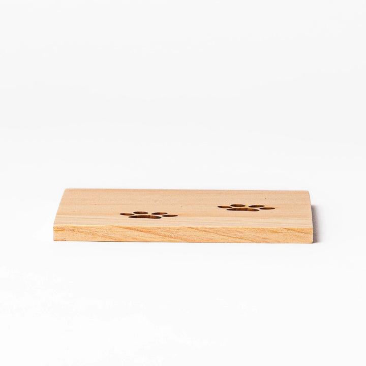 Square hinoki wood mini coaster with two cat paw cutouts, showcasing light grain and protecting surfaces.