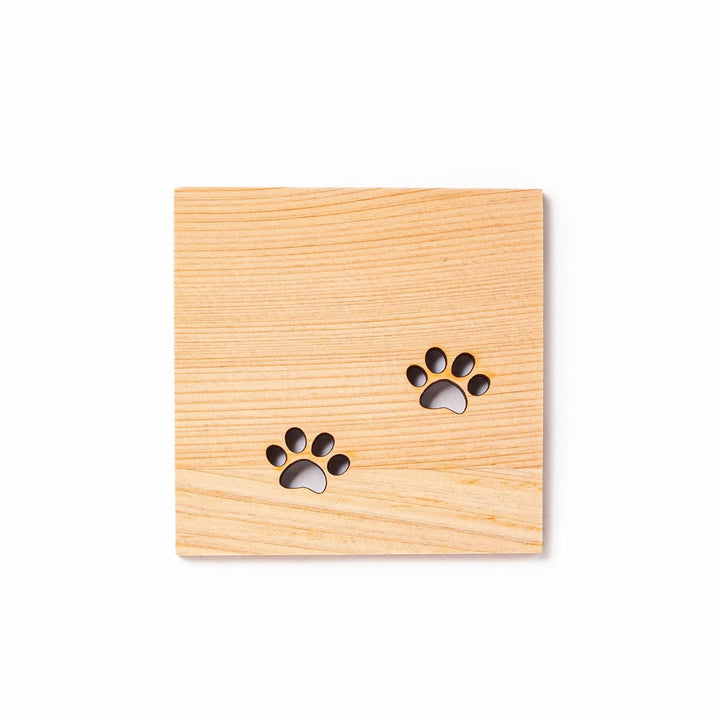 Square hinoki wood mini coaster with two cat paw cutouts, showcasing light grain and protecting surfaces.