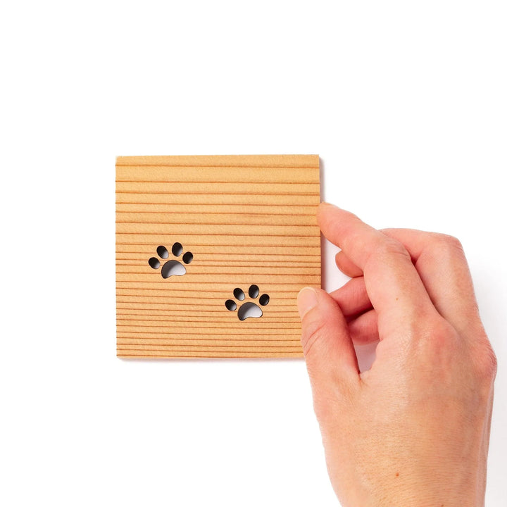Square cedar mini coaster with two laser-cut cat paw prints, natural warm wood grain, perfect for small cups or glasses.