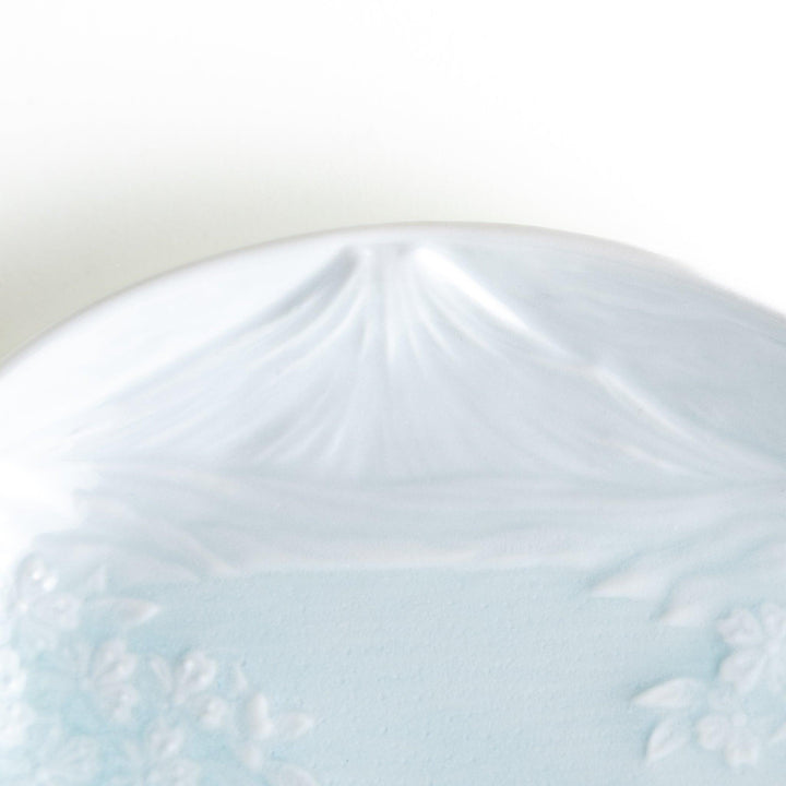 Round celadon dessert plate with raised Mount Fuji pattern and glossy finish symbolizing Japanese nature.