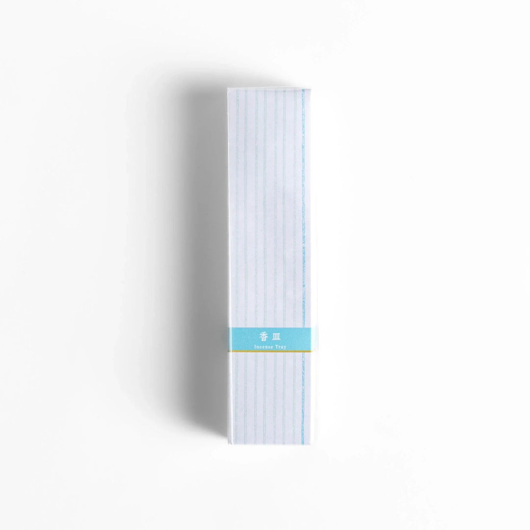 Japanese incense holder in minimalist white box with subtle stripes and light blue label for serene use.