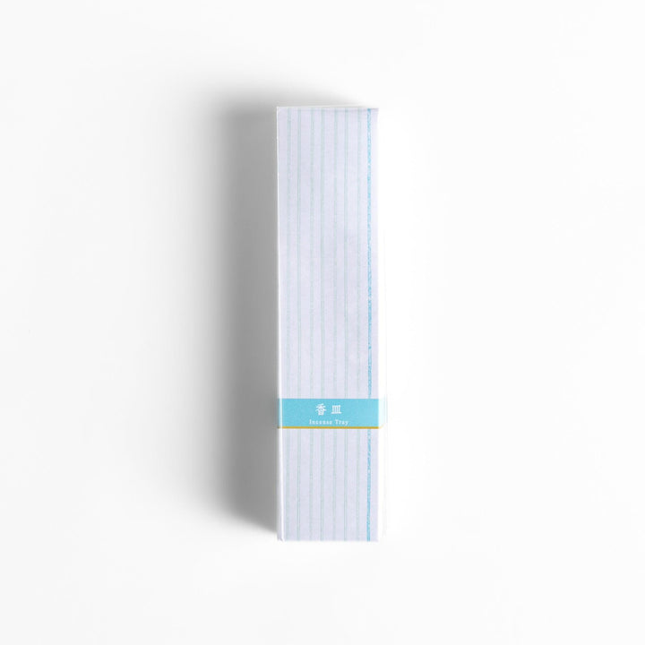 Japanese incense holder in minimalist white box with subtle stripes and light blue label for serene use.