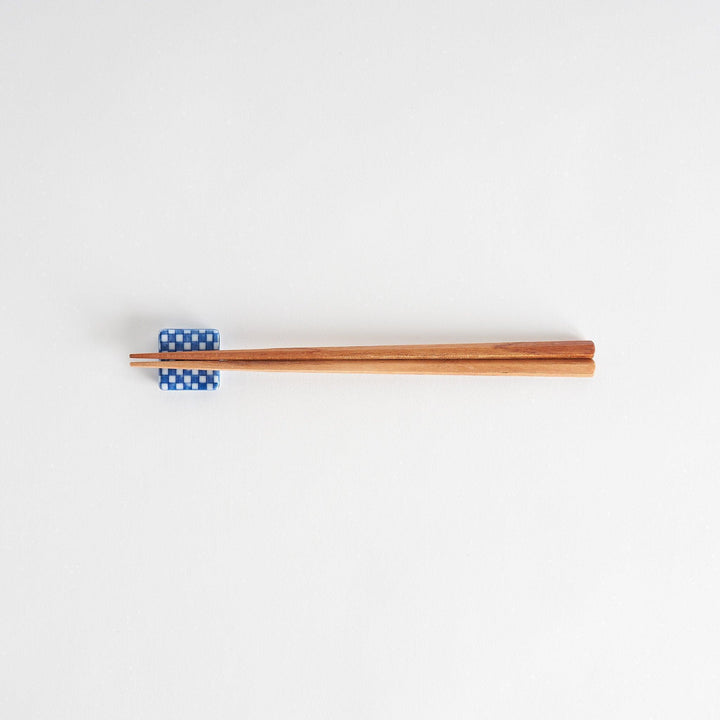 A blue and white checkered square-shaped ceramic chopstick rest.
