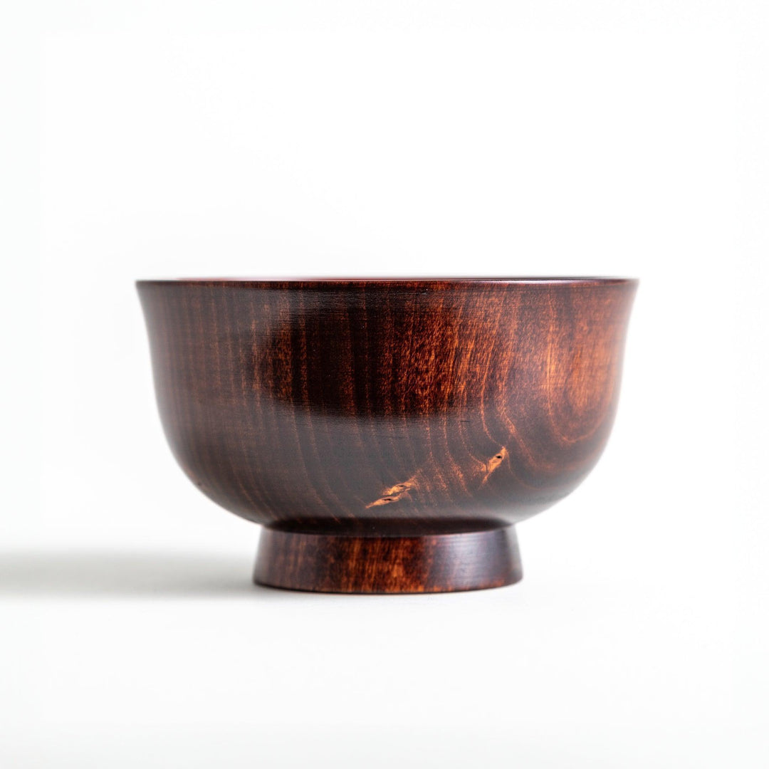 A wooden soup bowl with a rich, brown grain finish and a deep red interior.