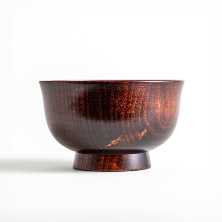 A wooden soup bowl with a rich, brown grain finish and a deep red interior.