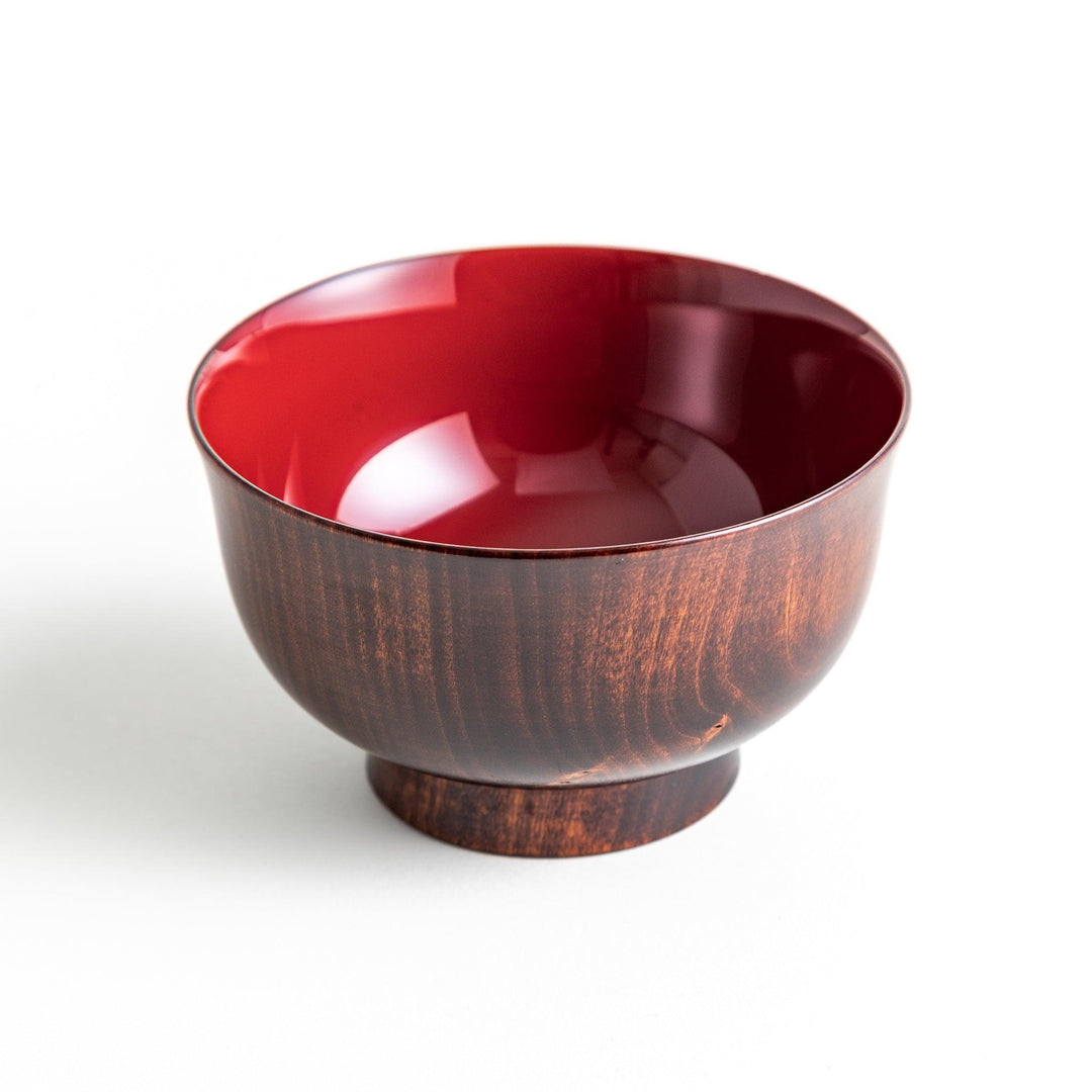 A wooden soup bowl with a rich, brown grain finish and a deep red interior.