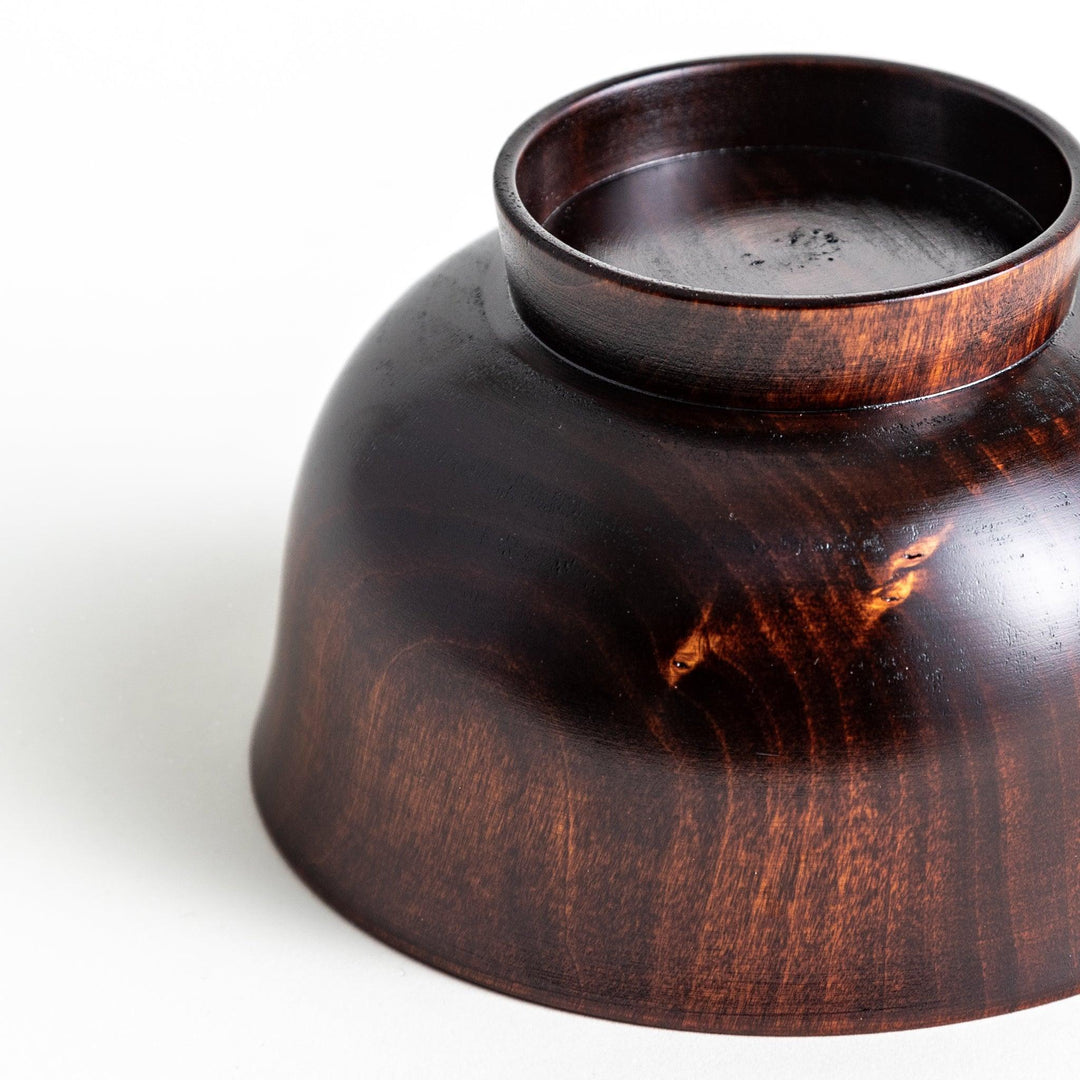A wooden soup bowl with a rich, brown grain finish and a deep red interior.