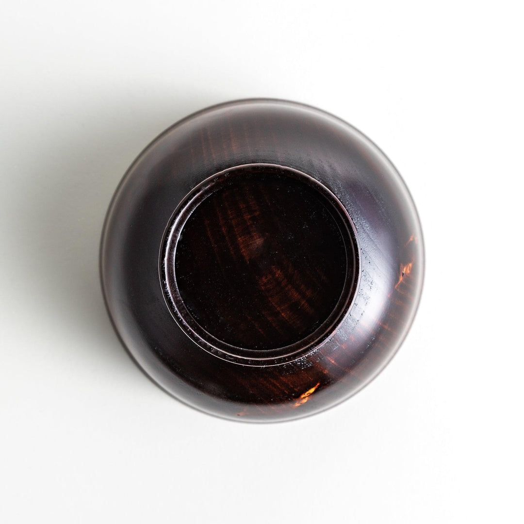 A wooden soup bowl with a rich, brown grain finish and a deep red interior.