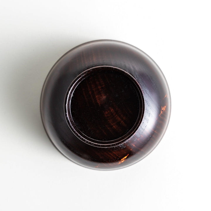 A wooden soup bowl with a rich, brown grain finish and a deep red interior.