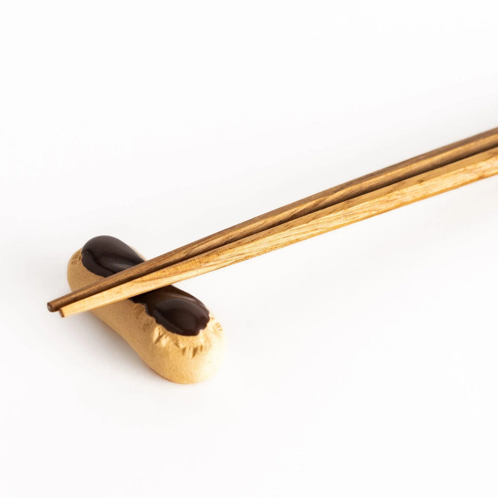 Chocolate éclair chopstick rest with golden brown base and glossy chocolate top featuring realistic details.
