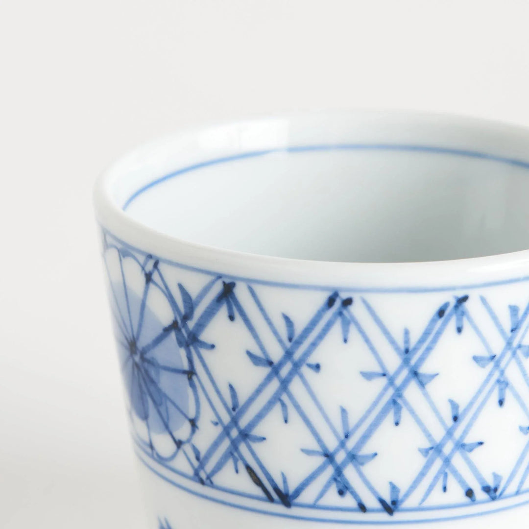 A small white condiment bowl with a delicate blue chrysanthemum and lattice pattern on the exterior.