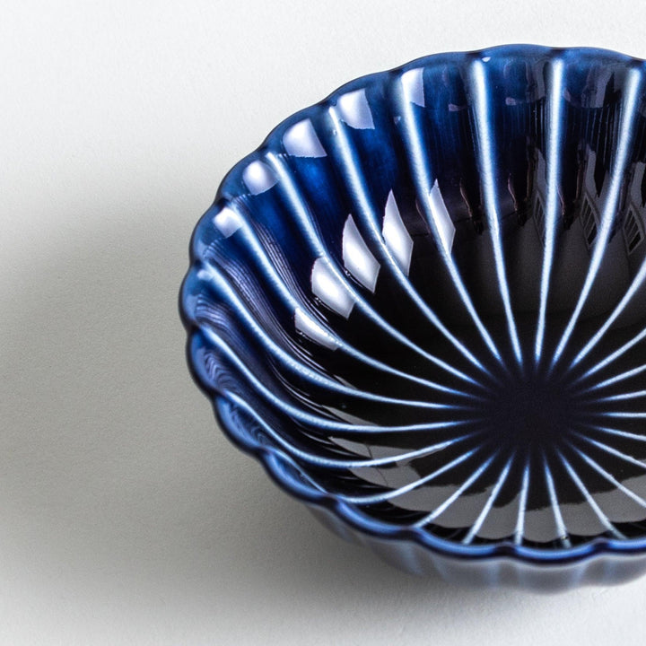 A blue dessert bowl featuring a ribbed pattern from the center outward.