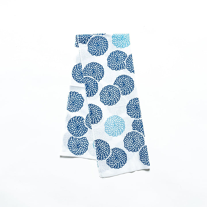 Blue chrysanthemum-patterned tenugui hand towel with white accents, neatly folded.