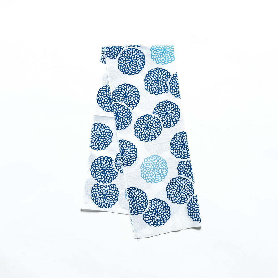 Blue chrysanthemum-patterned tenugui hand towel with white accents, neatly folded.