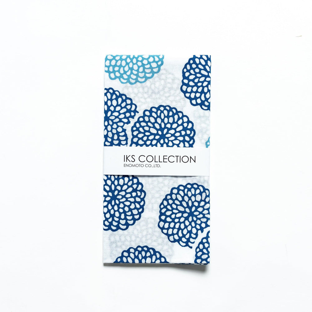Blue chrysanthemum-patterned tenugui, partially folded with product sleeve attached.