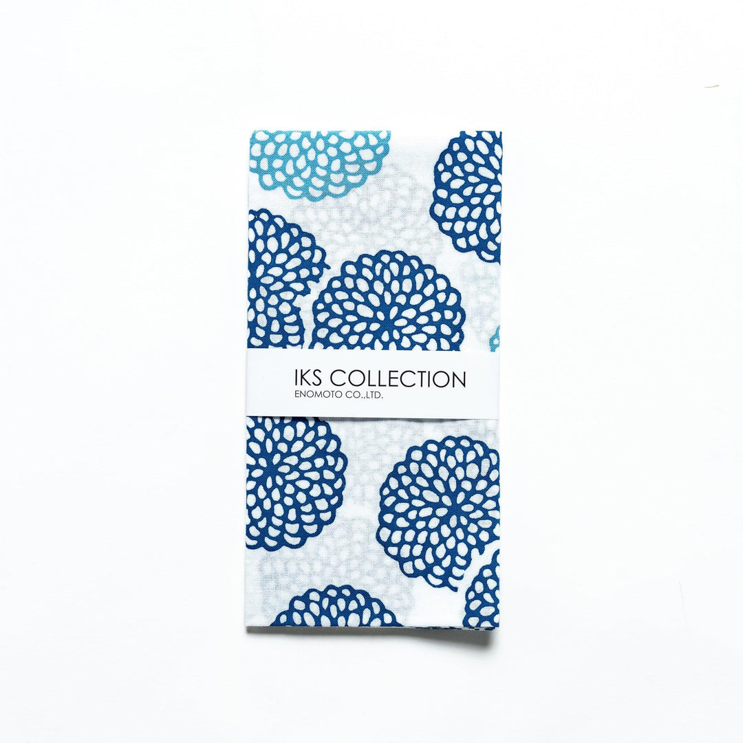 Blue chrysanthemum-patterned tenugui, partially folded with product sleeve attached.
