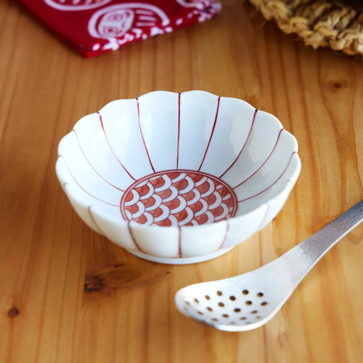 Japanese porcelain bowl with scalloped rim and red scale pattern interior, paired with hammered stainless steel straining spoon.