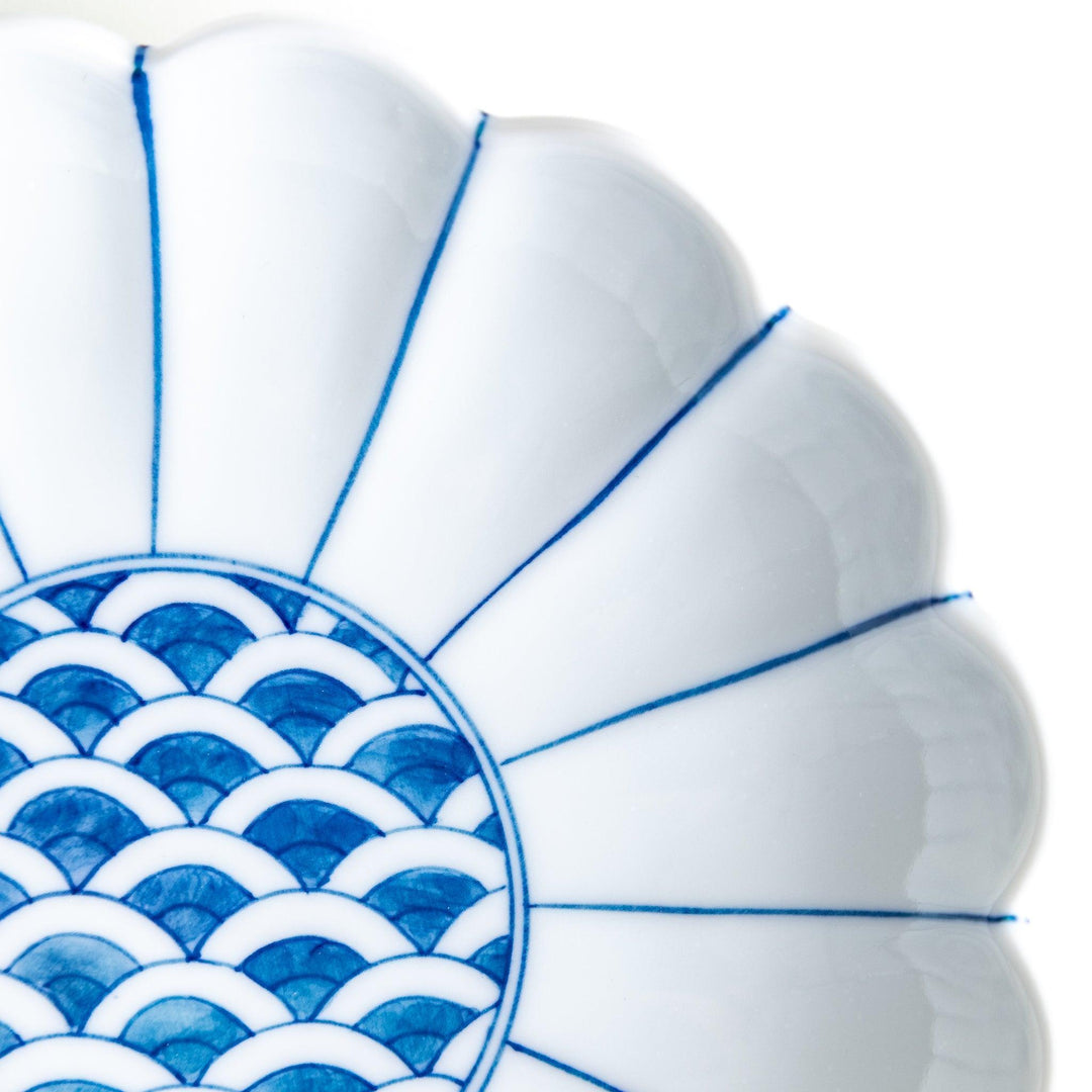 A scalloped-edged green plate with a blue and white wave pattern in the center.