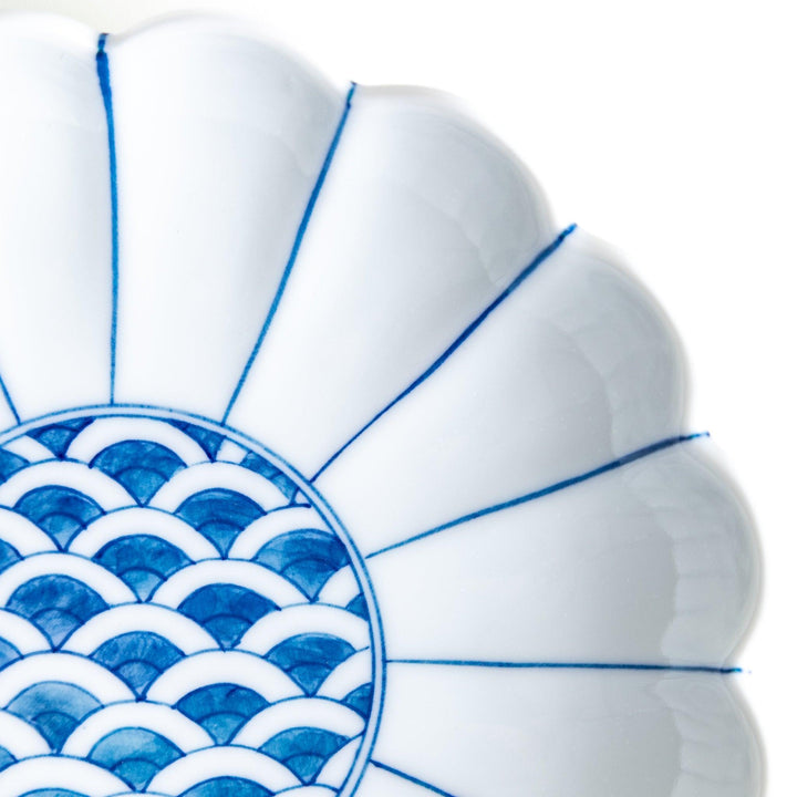 A scalloped-edged green plate with a blue and white wave pattern in the center.