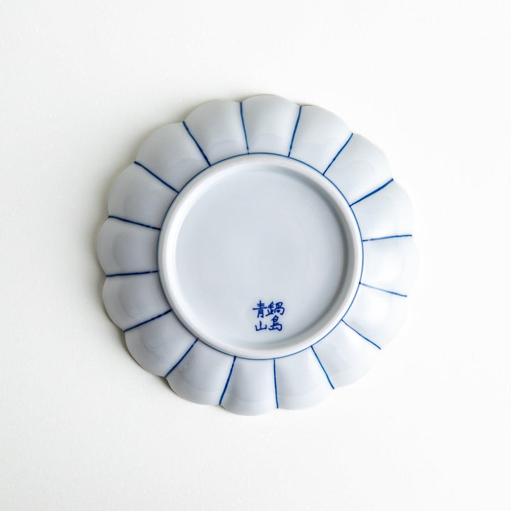 A scalloped-edged green plate with a blue and white wave pattern in the center.