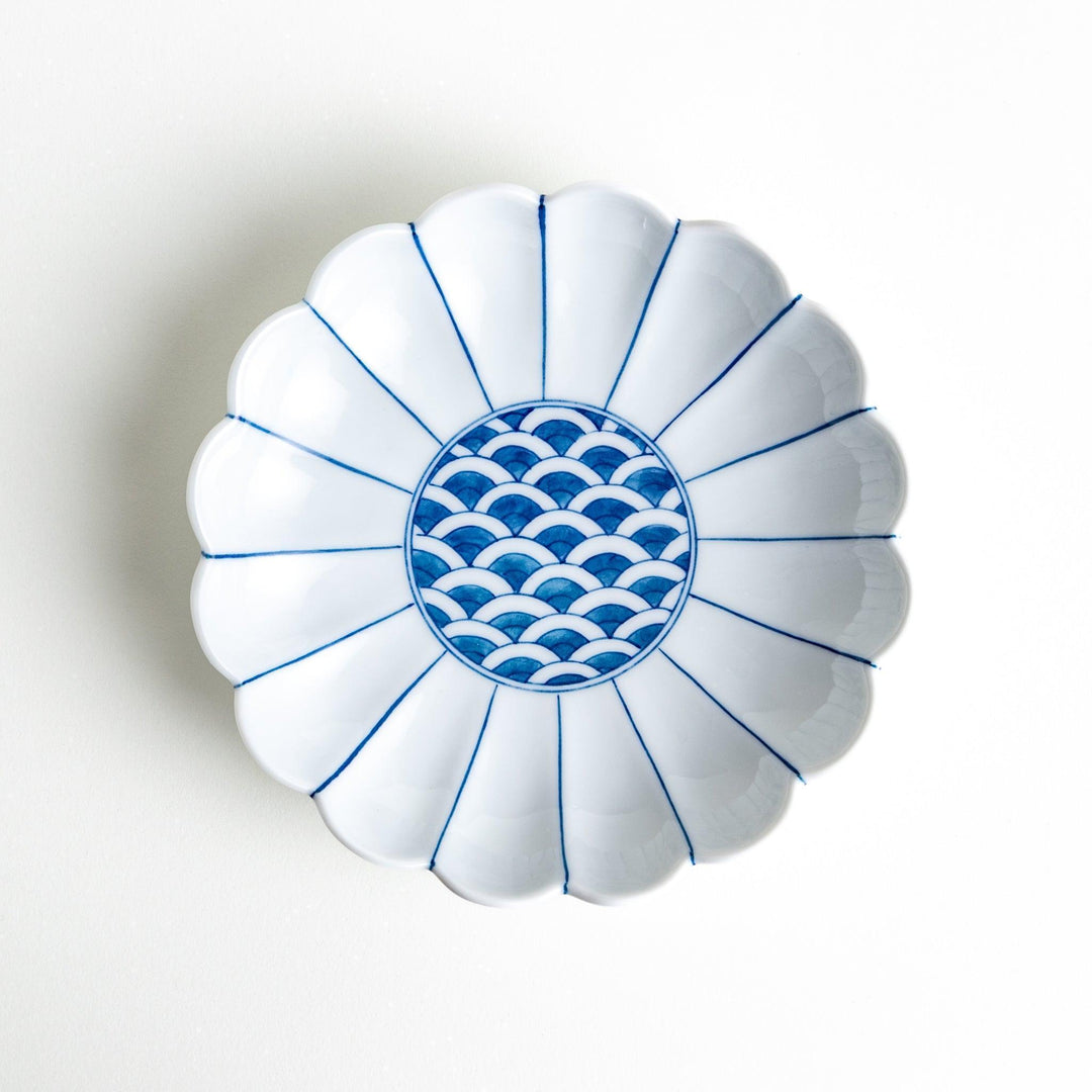 A scalloped-edged green plate with a blue and white wave pattern in the center.