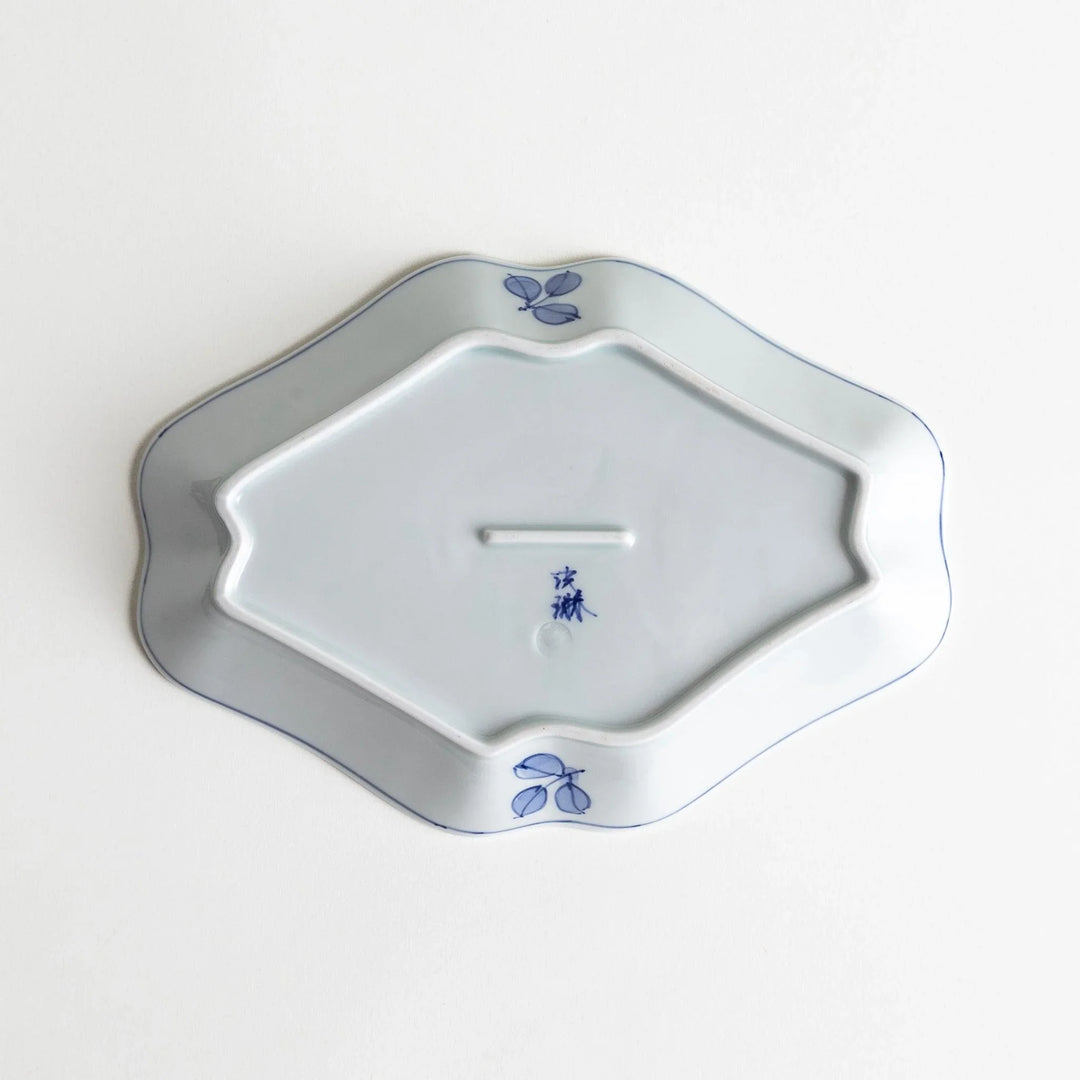 An irregularly shaped porcelain dish featuring hand-painted designs of fish and plants.