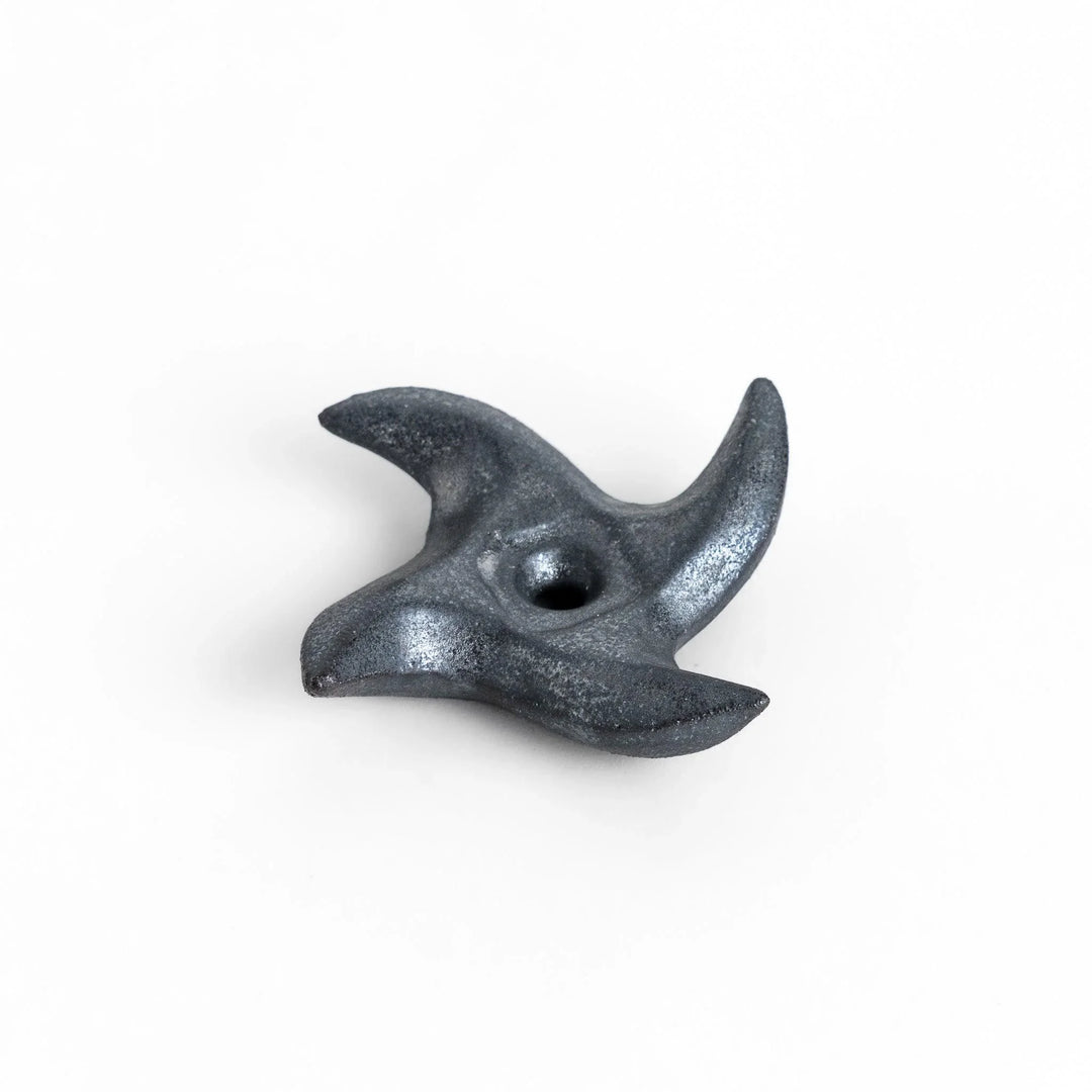 Metallic ninja star chopstick rest with sleek sharp edges adding unique stylish touch to dining table.