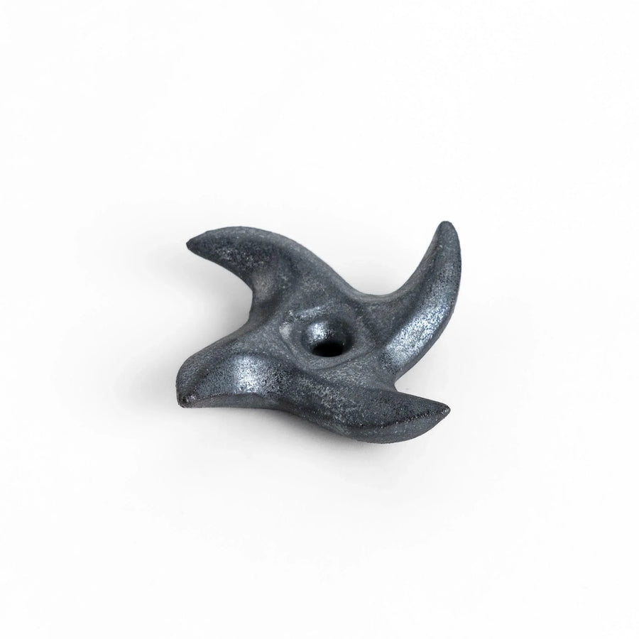 Metallic ninja star chopstick rest with sleek sharp edges adding unique stylish touch to dining table.