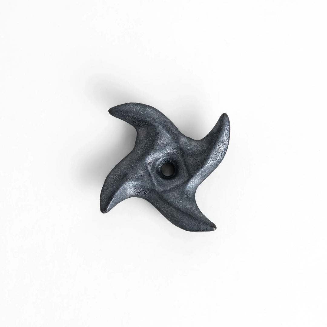 Metallic ninja star chopstick rest with sleek sharp edges adding unique stylish touch to dining table.