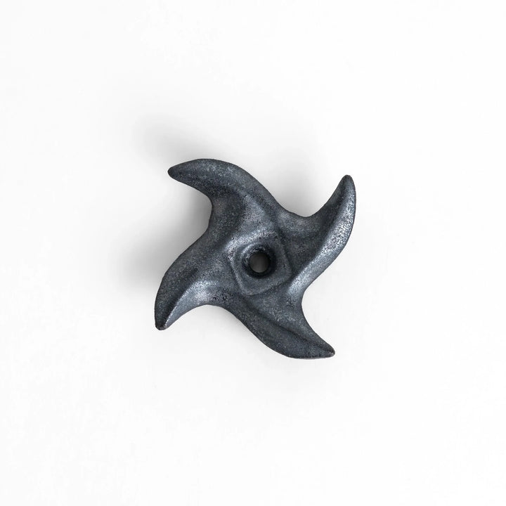 Metallic ninja star chopstick rest with sleek sharp edges adding unique stylish touch to dining table.