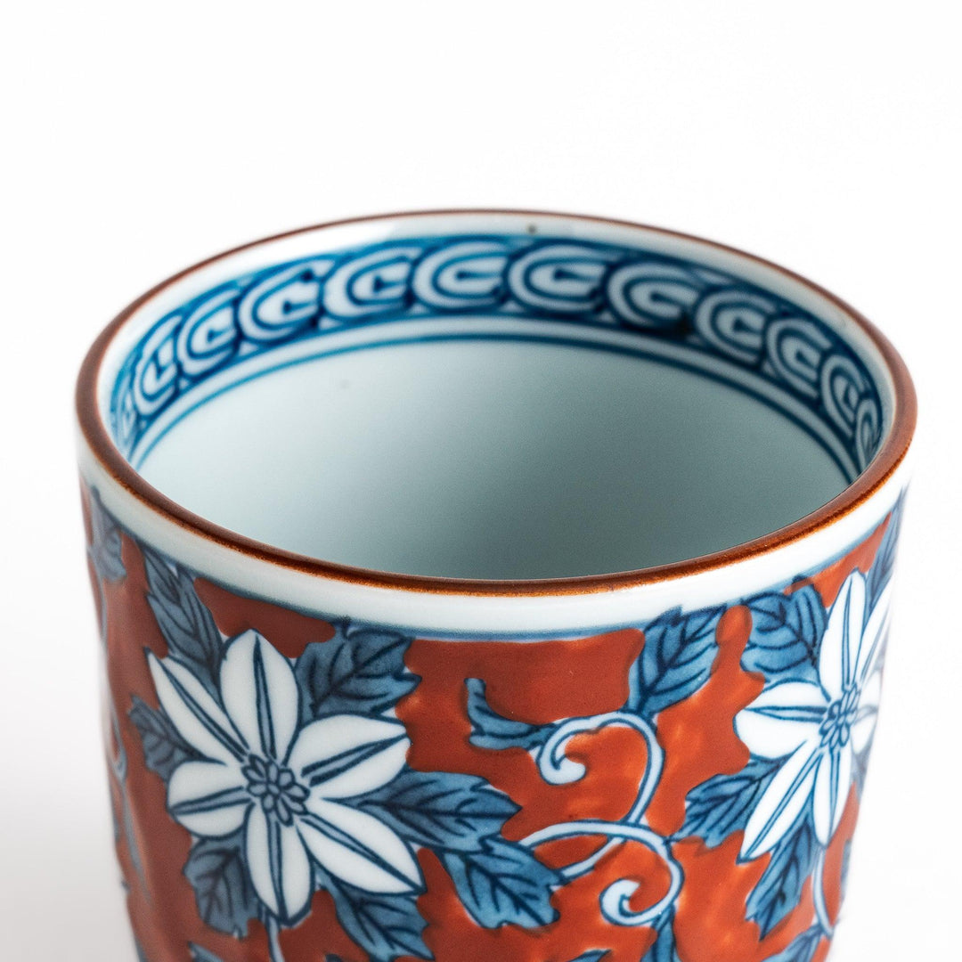 Hand painted teacup with red background and blue clematis flowers adding charm to Japanese tea service.