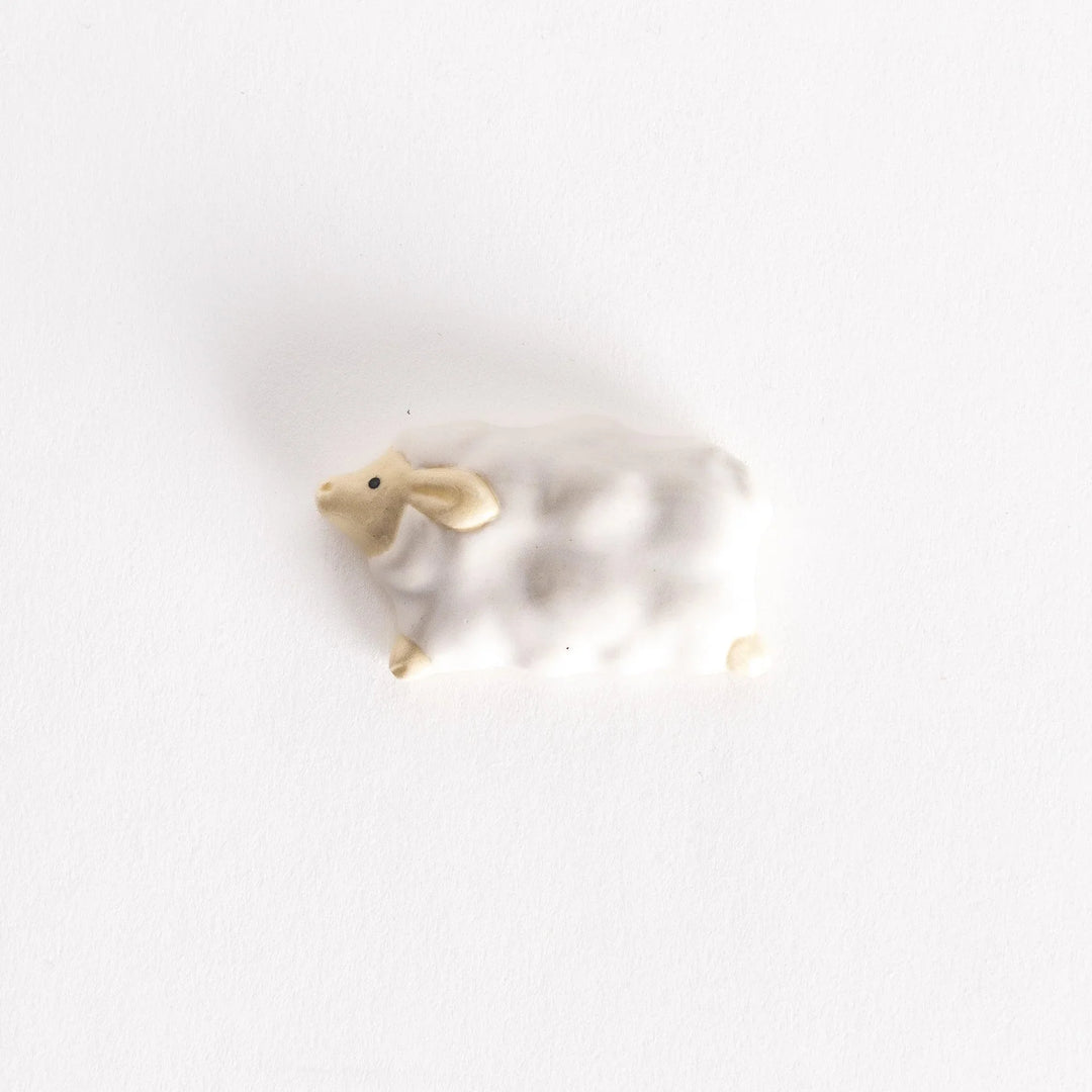 Ceramic sheep-shaped chopsticks rest featuring a fluffy white body and beige face, mimicking a cloud-like design.