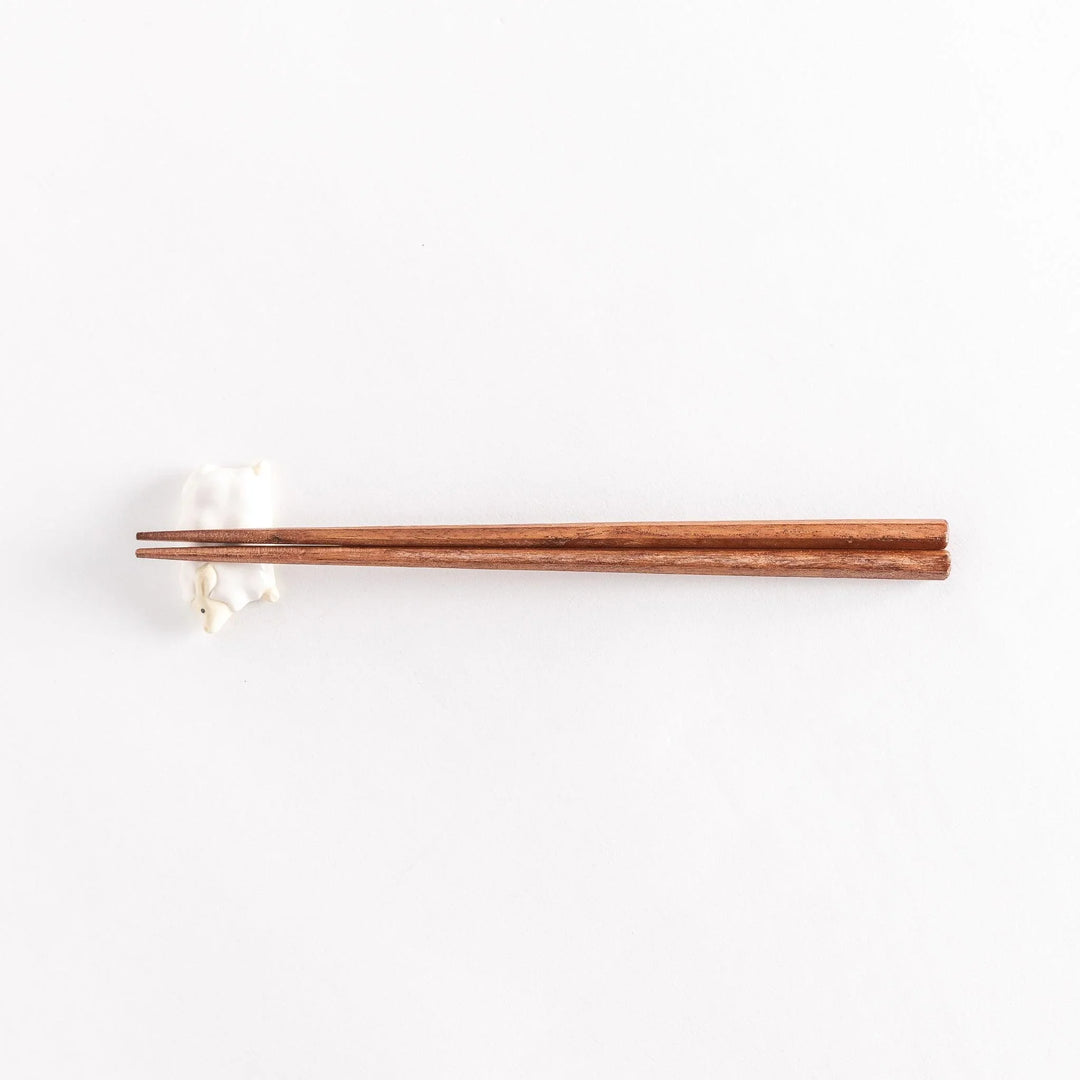 Full view of the sheep chopsticks rest with chopsticks resting across its soft, rounded body.