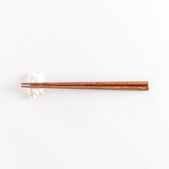 Full view of the sheep chopsticks rest with chopsticks resting across its soft, rounded body.