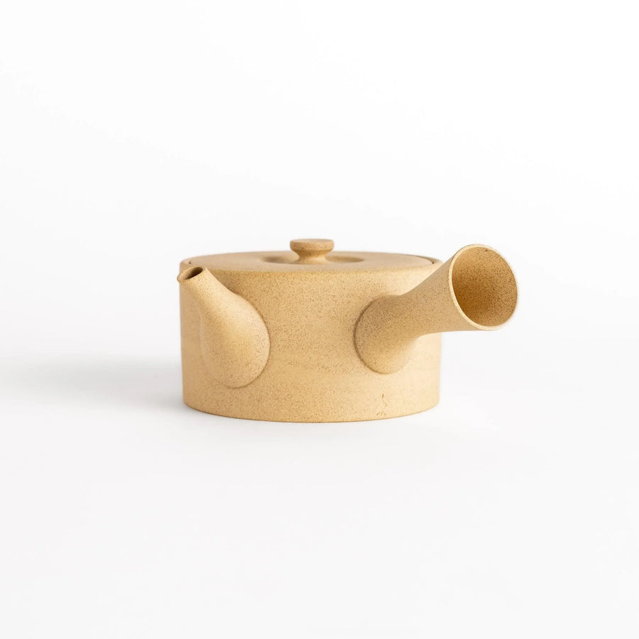 Minimalist beige teapot with horizontal spout and handle textured ceramic body for modern tea service.