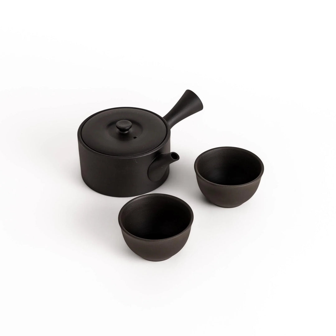 Minimalist black teapot with horizontal spout and textured ceramic finish for a refined tea experience.
