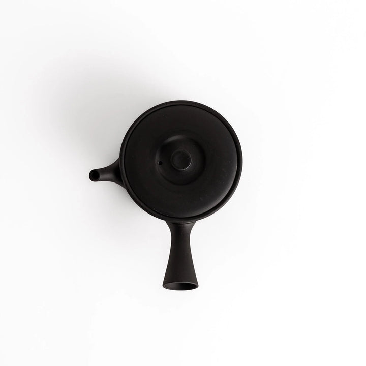 Minimalist black teapot with a horizontal spout and handle, crafted from textured ceramic, perfect for a refined tea experience.