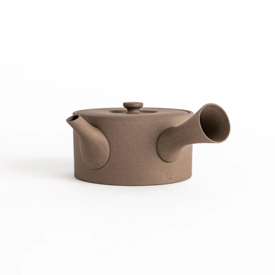 Minimalist gray teapot with horizontal spout and textured ceramic design for a refined tea experience.