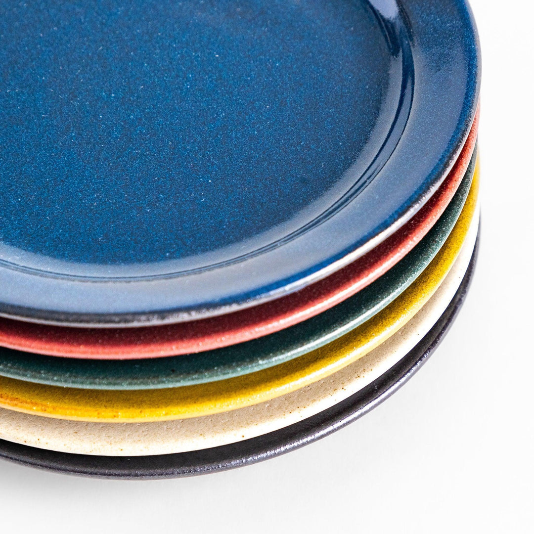 Stacked colorful Japanese ceramic dessert plates with glossy glaze in blue, red, green, yellow, and cream tones.