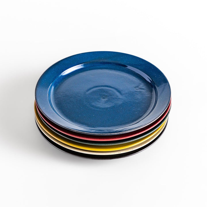 Stacked Japanese ceramic dinner plates in blue, red, green, yellow, and black glazes showcasing modern craftsmanship.