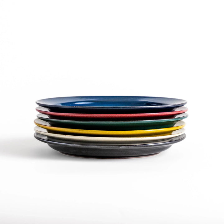 Stacked Japanese ceramic dinner plates in blue, red, green, yellow, and black glazes showcasing modern craftsmanship.
