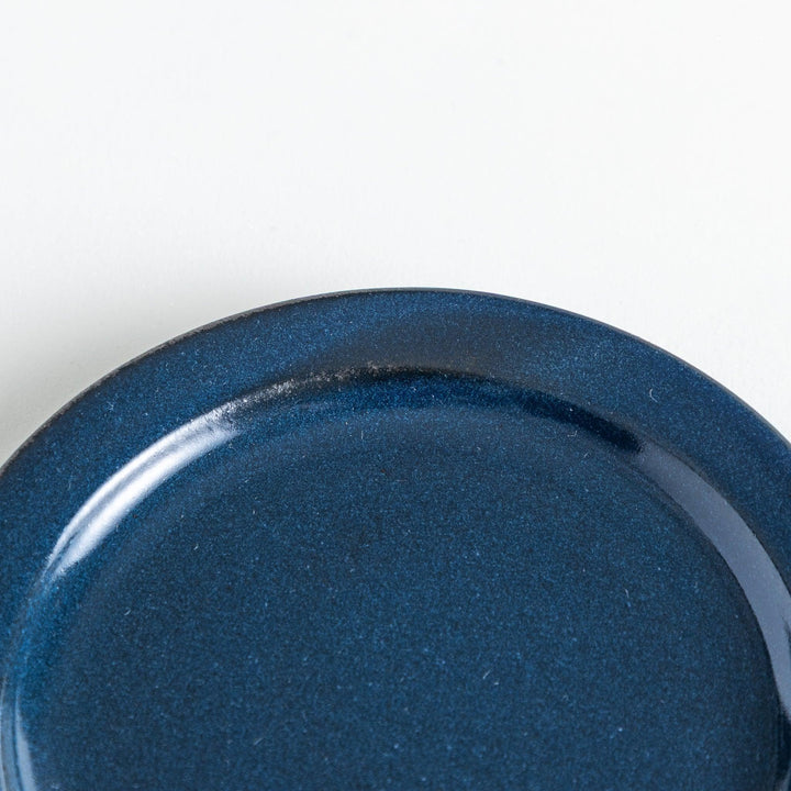 Dark navy plate with a lustrous shine, highlighted by the handmade feel of the uneven glaze near the rim.