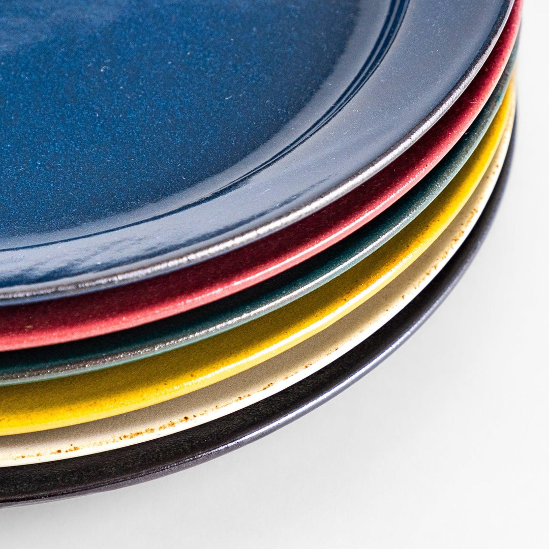 Six colorful Japanese dinner plates in blue red green yellow white and black stacked with glossy finish.