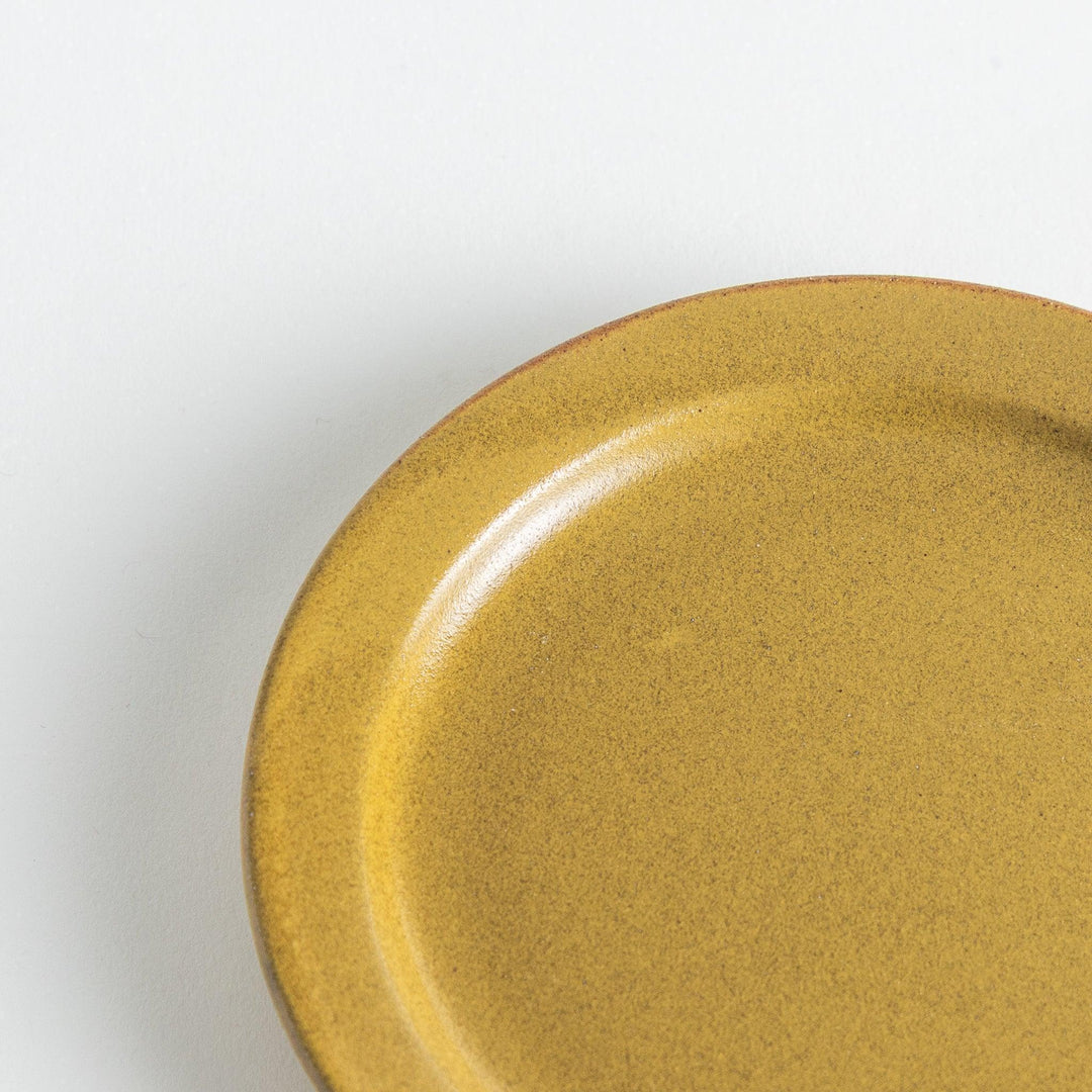 Yellow plate with a matte finish, showcasing handmade charm through the uneven glaze on its smooth rim.