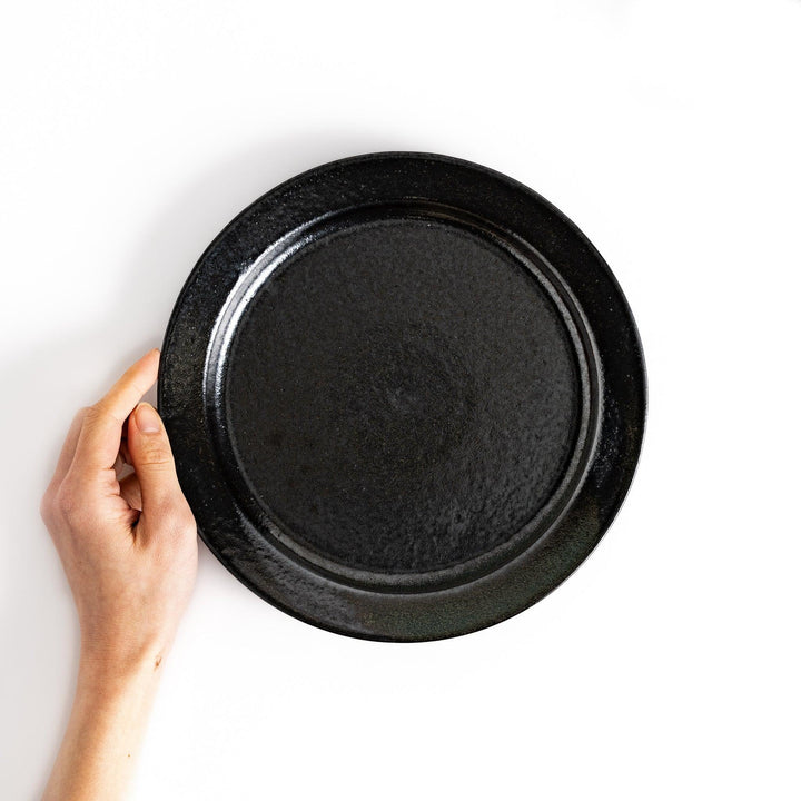 Black ceramic dinner plate with glossy finish and smooth texture offering minimalist elegance to any dining table.