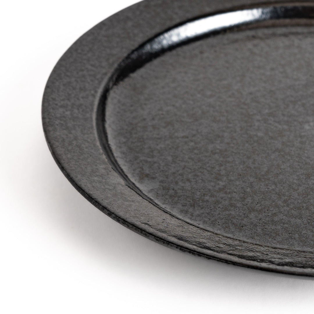 Black ceramic dinner plate with glossy finish and smooth texture offering minimalist elegance to any dining table.