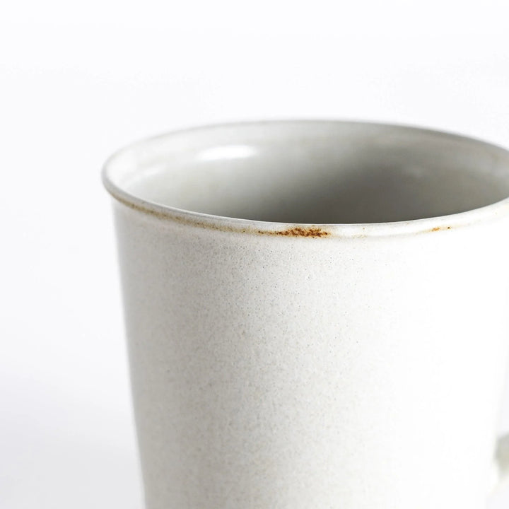 Close-up view of the white ceramic mug, emphasizing its glossy surface and neutral-toned base.