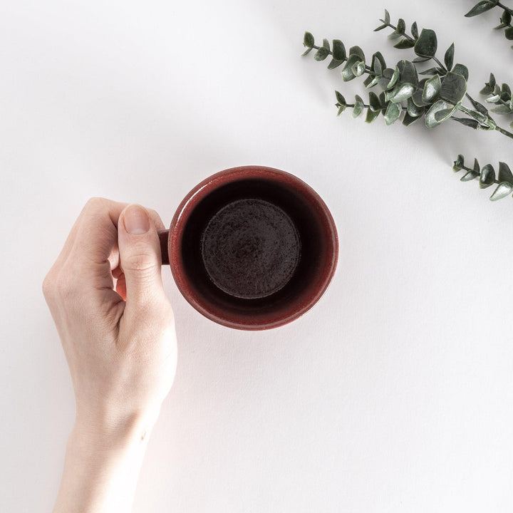Top-down view of a red ceramic mug held in hand, showcasing the circular opening and spacious interior.