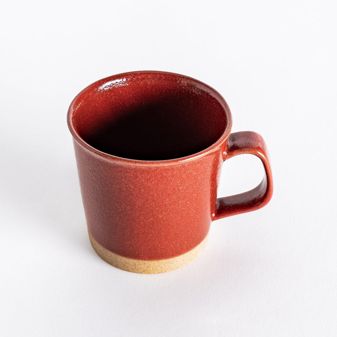 Colorful mug in blue red green yellow white or black with glossy finish and natural clay base on wooden block.