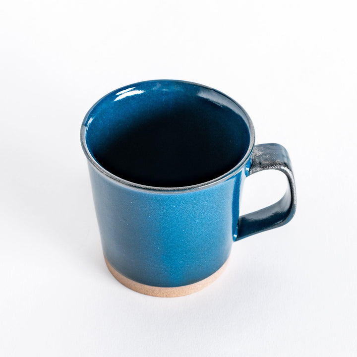 Slightly angled view of a blue ceramic mug, highlighting its smooth handle and the vibrant blue glaze.